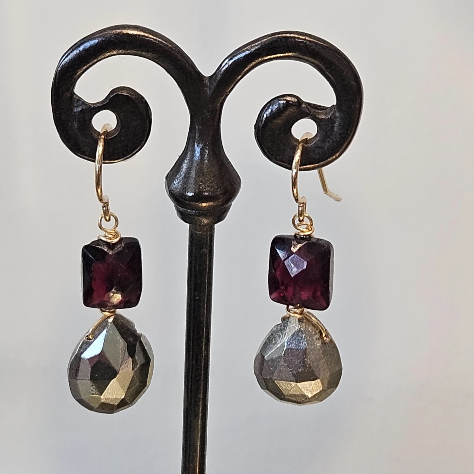 Handmade wire-wrapped earrings with faceted garnet and pyrite drops on gold hooks
